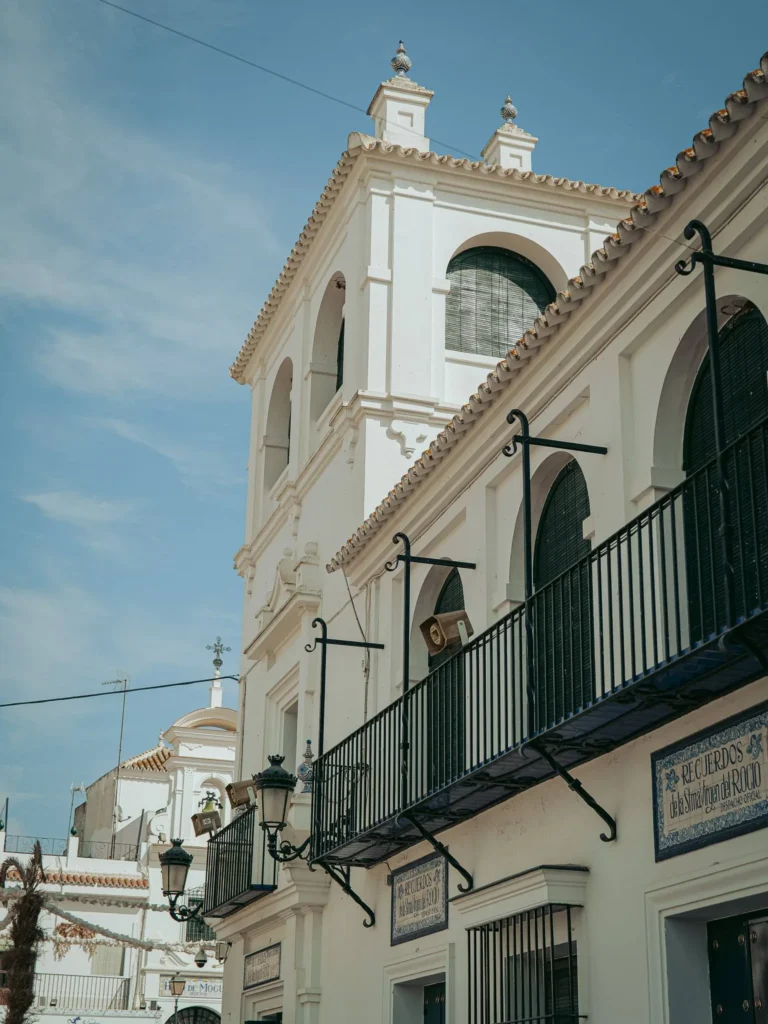 Fachada blanca, balcones y rejas oscuras en una calle de arena de El Rocío