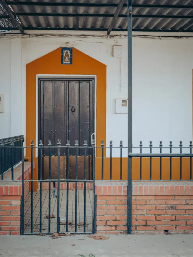 Puerta de madera oscura, marco ocre y cerámica religiosa sobre una entrada en El Rocío