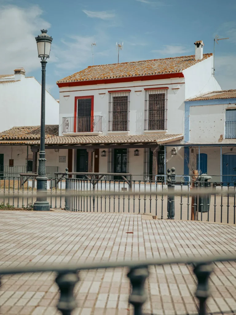Casa blanca, rejas y farola junto a una calle de arena de El Rocío