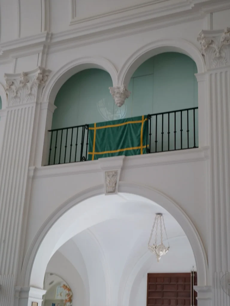 Colgadura verde con galones amarillos doblada sobre una barandilla del santuario del Rocío