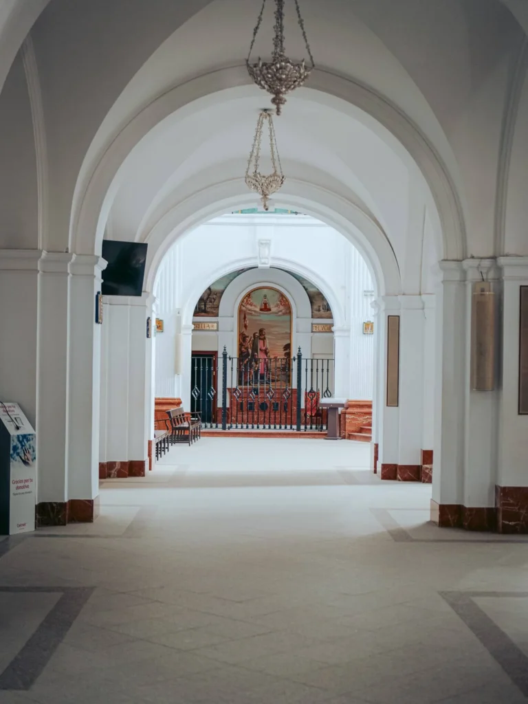 Arcos blancos y lámparas colgantes en una nave lateral del santuario del Rocío