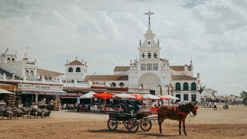 Coche de caballos y santuario blanco junto a la plaza de arena de El Rocío