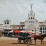 Coche de caballos y santuario blanco junto a la plaza de arena de El Rocío