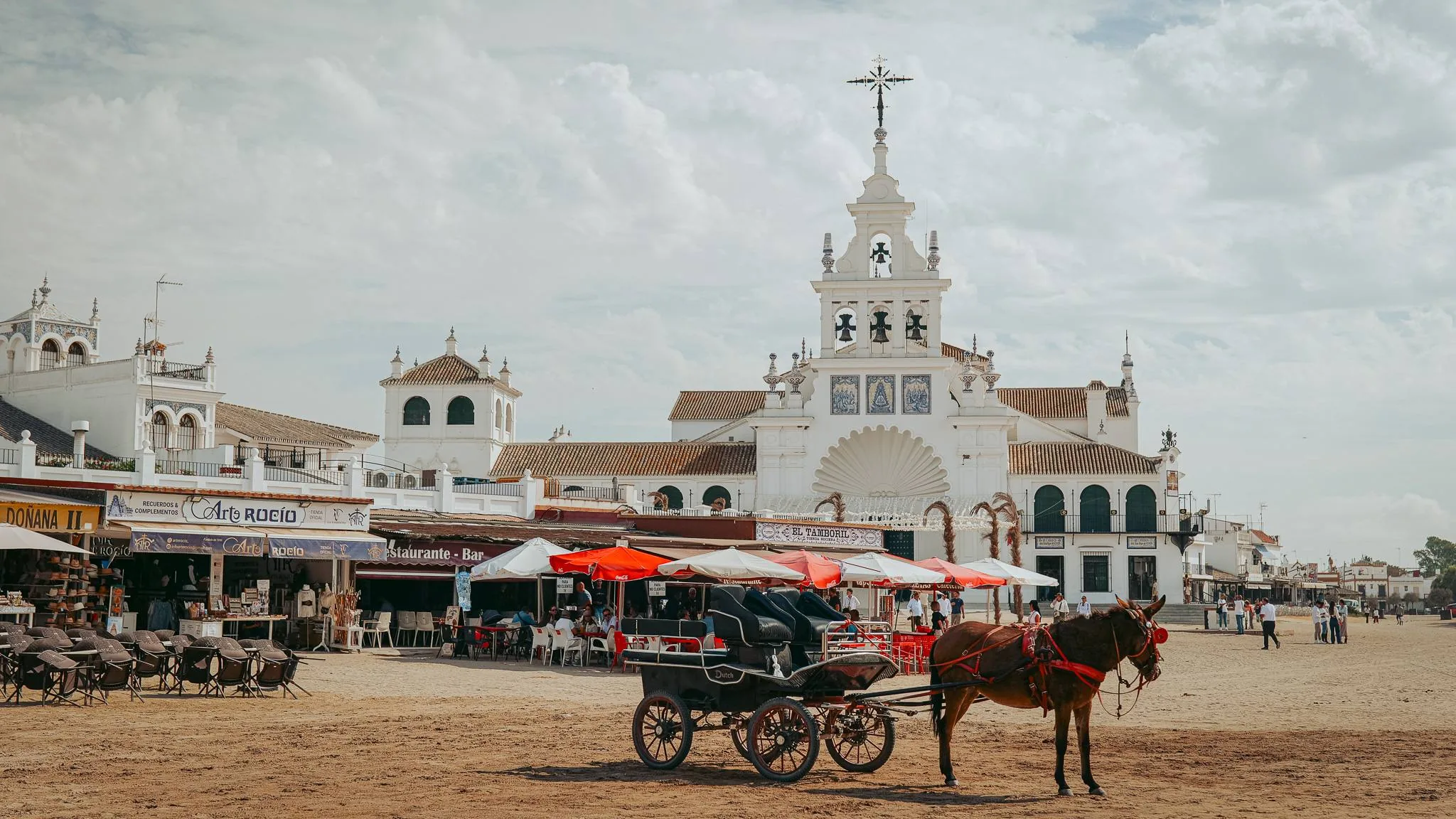 Coche de caballos y santuario blanco junto a la plaza de arena de El Rocío