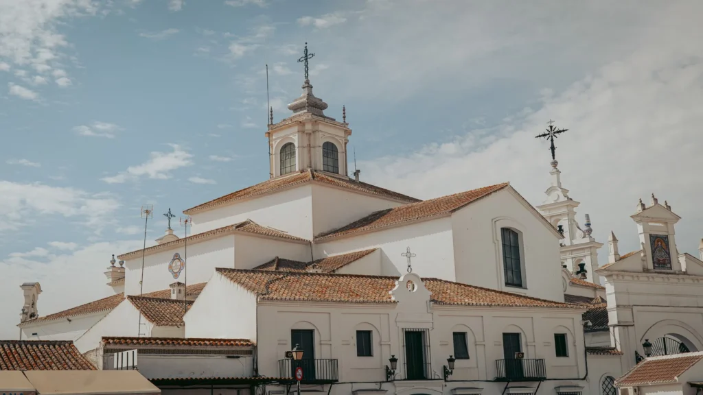 Vista lateral del santuario del Rocío con muros blancos, tejados y campanas